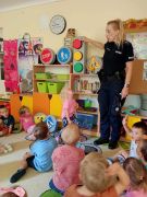 dzieci siedzą na dywanie słuchają pani Policjantki