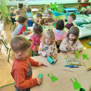 Dzieci wykonują ufoludki z papieru przy stolikach