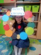 dziewczynka pozuje do zdjęcia w ramce w kropki.