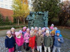 Dzieci pozują do zdjęcia przy pomniku.