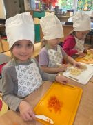 Dzieci wspólnie wykonują sałatkę w strojach kucharzy.