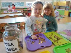 Dwie dziewczynki pozują do zdjęcia segregując grosze.