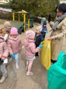 Dzieci sprzątają okolice przedszkola segregują śmieci.