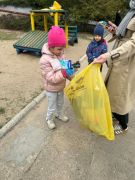 Dzieci sprzątają okolice przedszkola segregują śmieci.