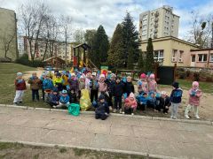 Dzieci sprzątają okolice przedszkola segregują śmieci.