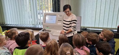 Dzieci słuchają pracownicę banku.
