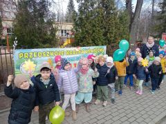 Dzieci pozują do zdjęcia z balonami i innymi wiosennymi atrybutami.