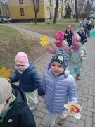 Dzieci idą parami z kwiatami w ręku.
