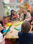 Rodzice wraz z dziećmi pracują przy stoliku.